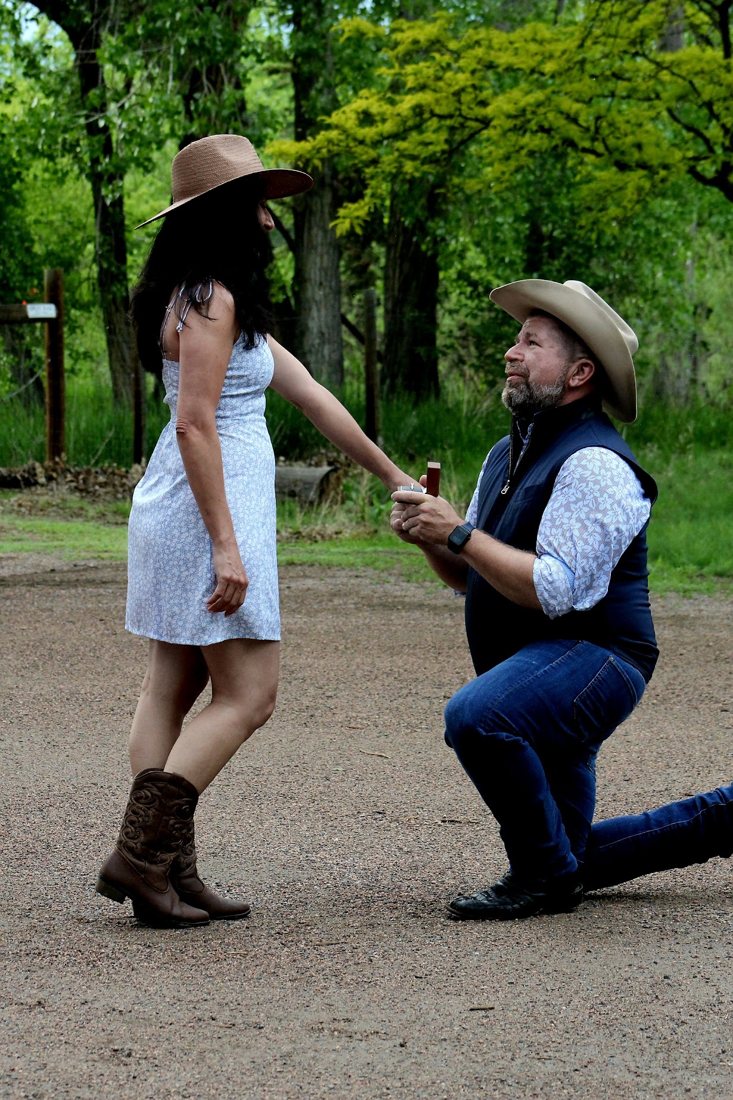 A proposal on one knee on a gravel path among spring trees